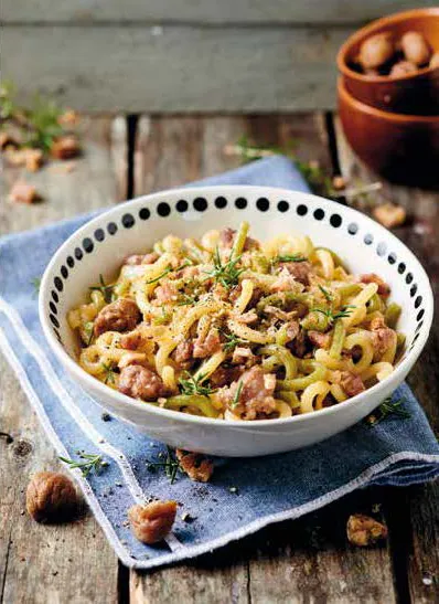 Fotografia del piatto di Paglia e fieno con salsiccia, castagne sbriciolate e rosmarino su una tavola apparecchiata